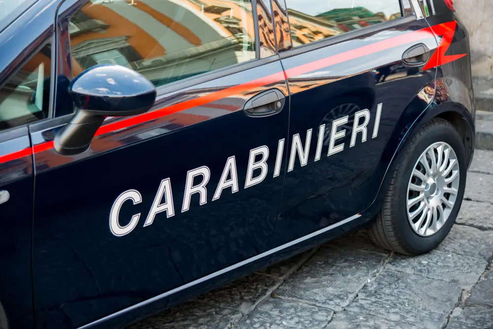 Dettaglio della fiancata di una vettura dei Carabinieri con la scritta bianca sulla tipica livrea blu e rossa.