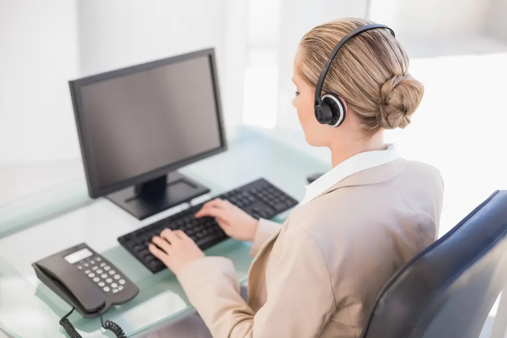 Agente della Polizia di Stato al lavoro in un ufficio della questura con computer e cuffie.