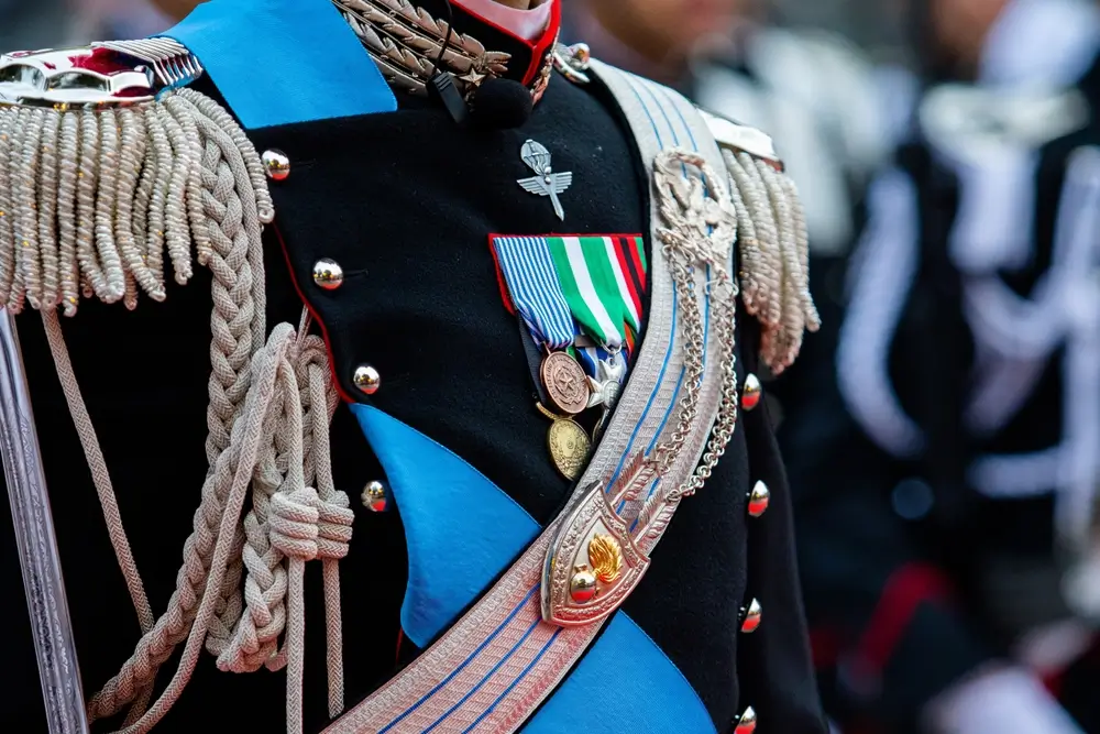 Uniforme dei Carabinieri con medaglie e spalline, dettaglio dei distintivi di grado e del ruolo maresciallo.