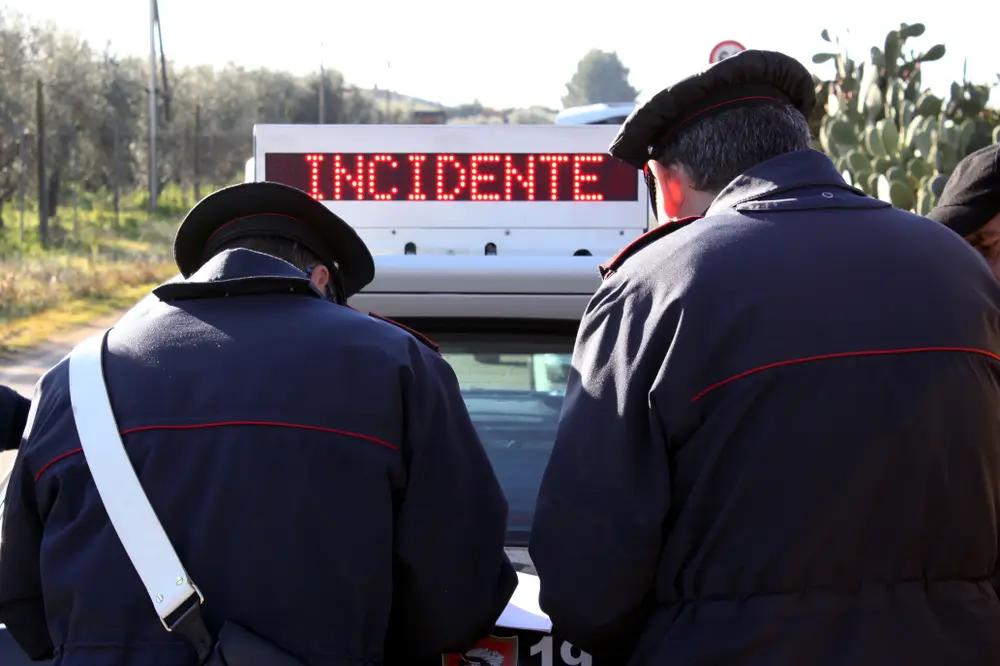 Due carabinieri in servizio di pattuglia accanto a un veicolo con la scritta luminosa incidente stradale.