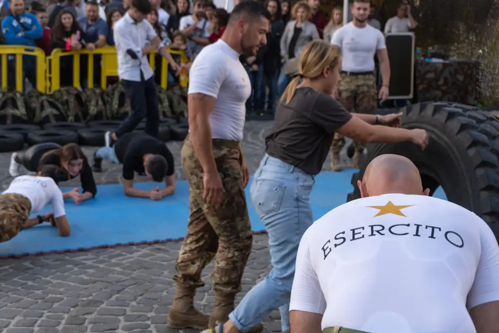 Addestramento fisico militare con esercizi di plank e ribaltamento di pneumatici per aspiranti allievi carabinieri.