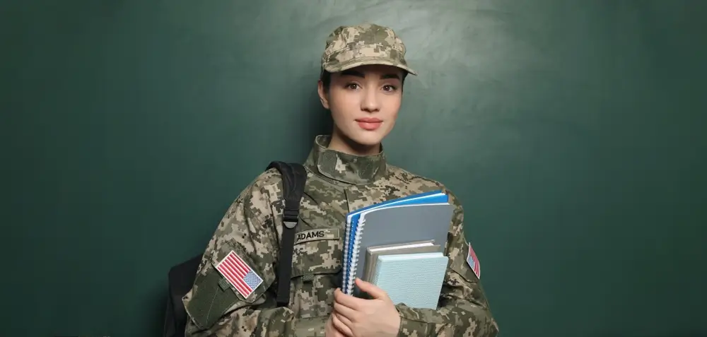 Allieva ufficiale dell'Accademia Militare in divisa mimetica con libri, durante una lezione di formazione.