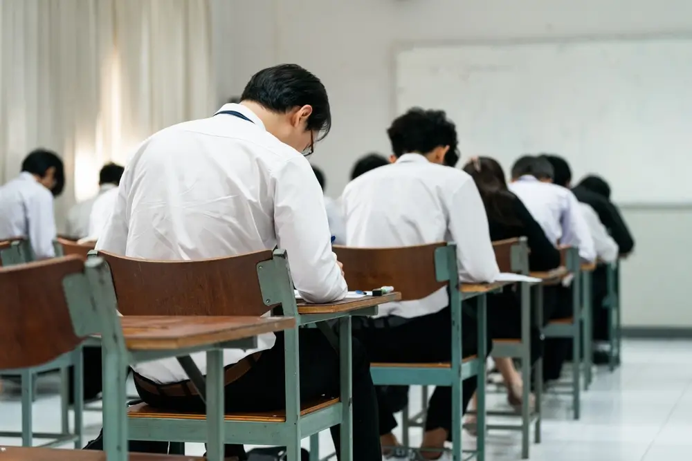Candidati seduti ai banchi di un'aula concorso durante lo svolgimento di una prova d'esame scritta.