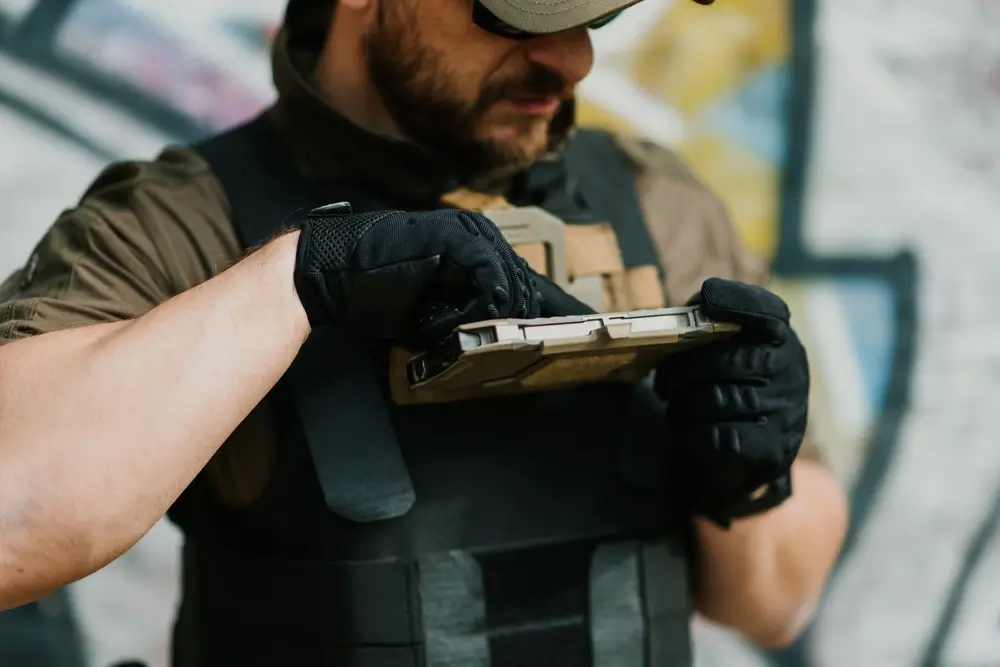 Carabiniere in divisa operativa che utilizza un tablet tattico professionale fissato alla sua attrezzatura militare.