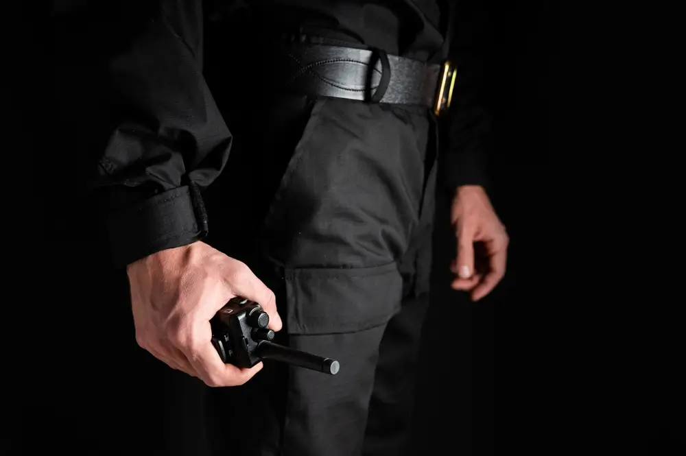 Carabiniera in divisa operativa che impugna una radio ricetrasmittente, tipica attrezzatura di servizio dei Carabinieri.