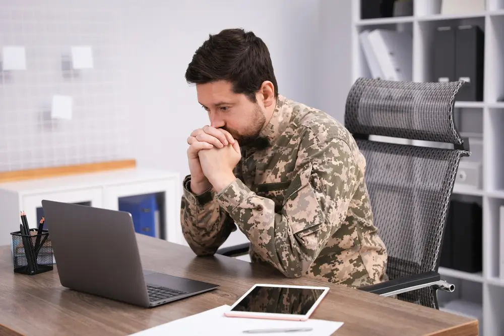 Militare studia concentrato su laptop e tablet per la preparazione ai quiz del concorso interno dei Carabinieri.