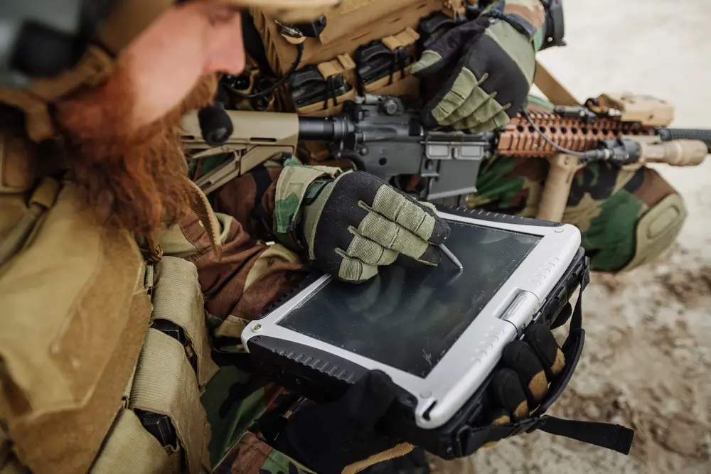 Ufficiale militare utilizza un tablet rugged con una penna durante un'esercitazione tecnologica sul campo.